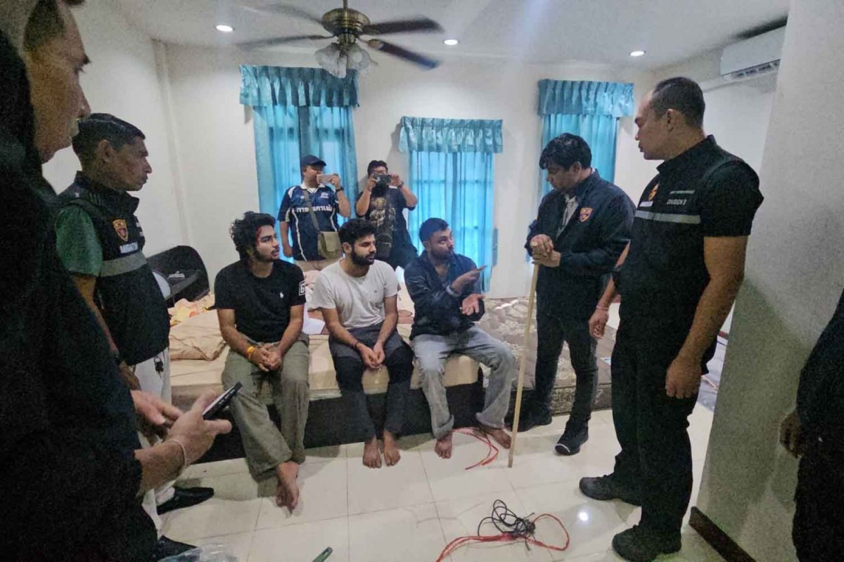 Thai police standing around three rescued Indian tourists inside the Nong Prue townhouse in Pattaya where they were held for ransom