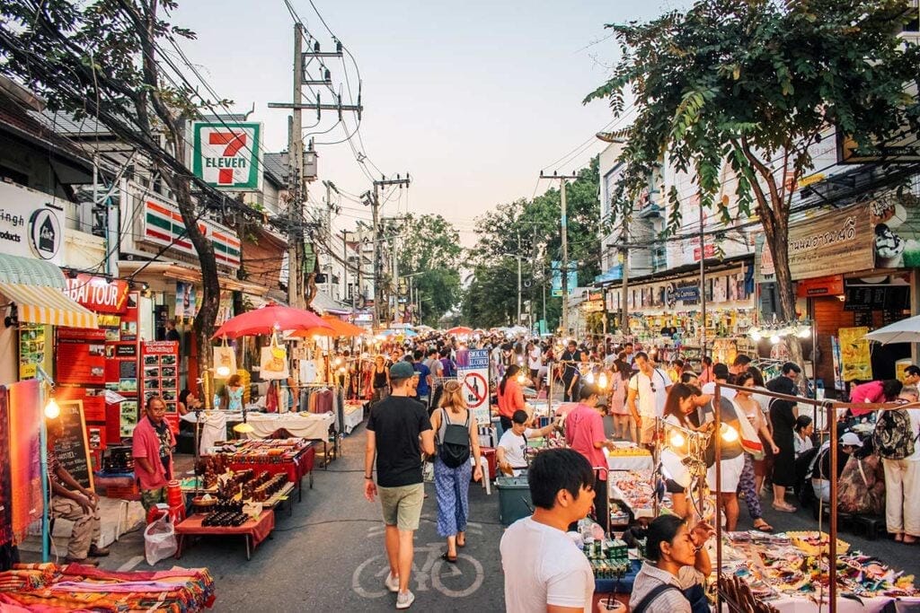 A busy Thai night market lined with street-food stalls and warm lights